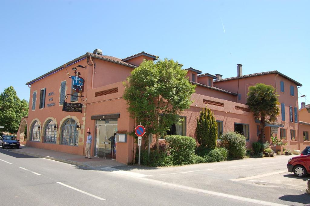 een man die voor een gebouw op straat staat bij Hotel Restaurant des Thermes in Castéra-Verduzan