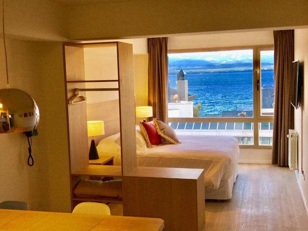 a hotel room with a bed and a large window at MINI LOFT Departamentos Bariloche in San Carlos de Bariloche