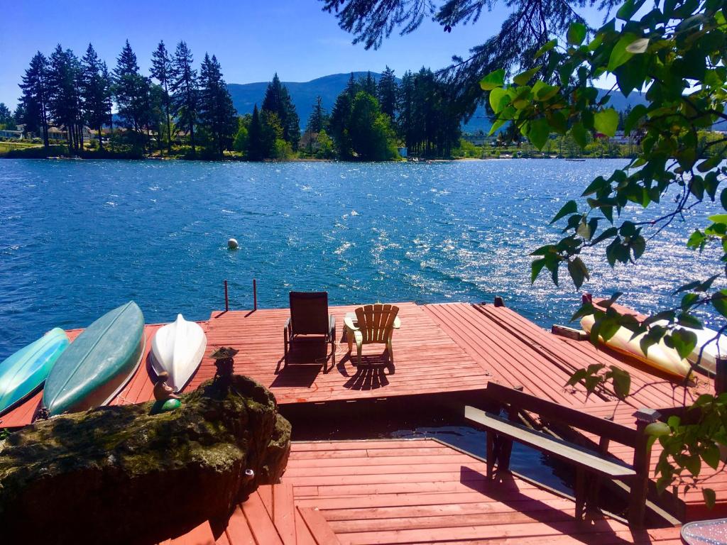 a dock with two chairs and a boat on a lake at Long Lake Waterfront Bed and Breakfast in Nanaimo