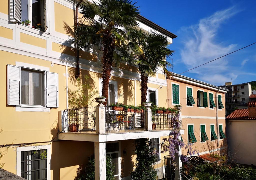 a building with a balcony and a palm tree at Le Palme Trieste in Trieste