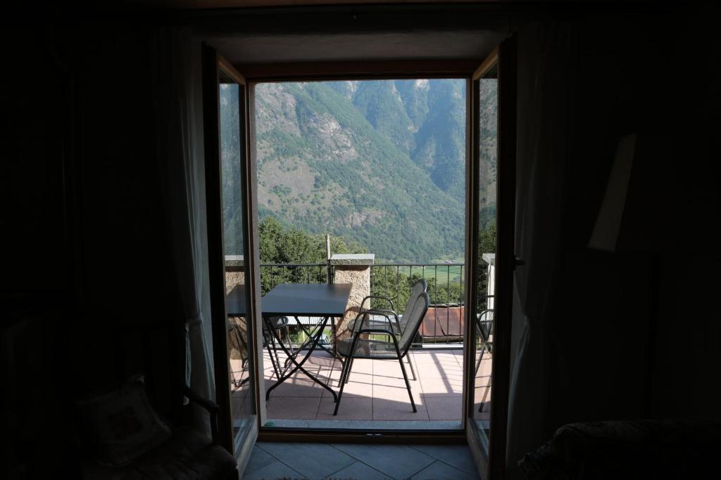a door leading to a balcony with a table and chairs at Casa Flora in Verdabbio