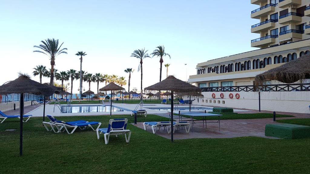 un resort con piscina, sedie e un edificio di Apartamento en Benalmádena a Benalmádena
