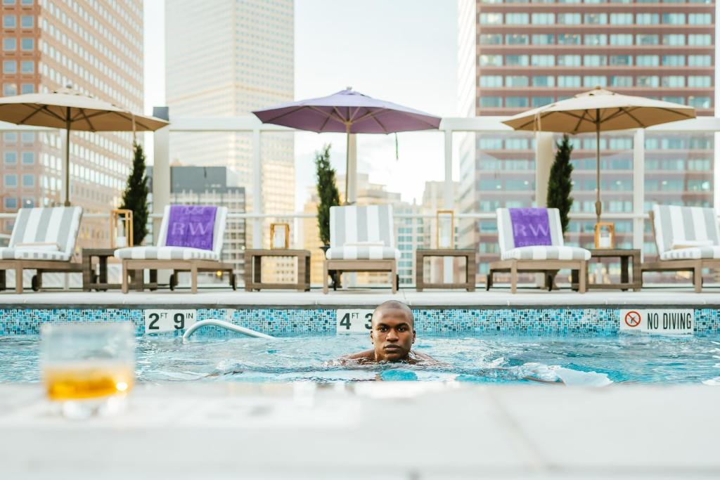 a man in a swimming pool in a city at Warwick Denver in Denver