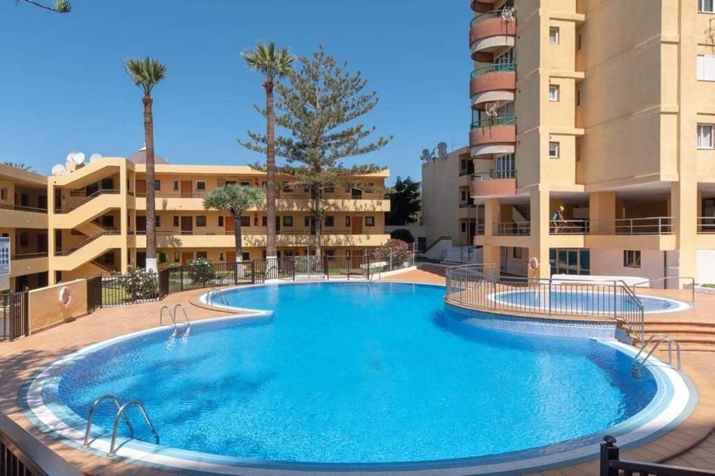 una gran piscina frente a algunos edificios de apartamentos en Torres del Sol Edificio, en Playa de las Américas