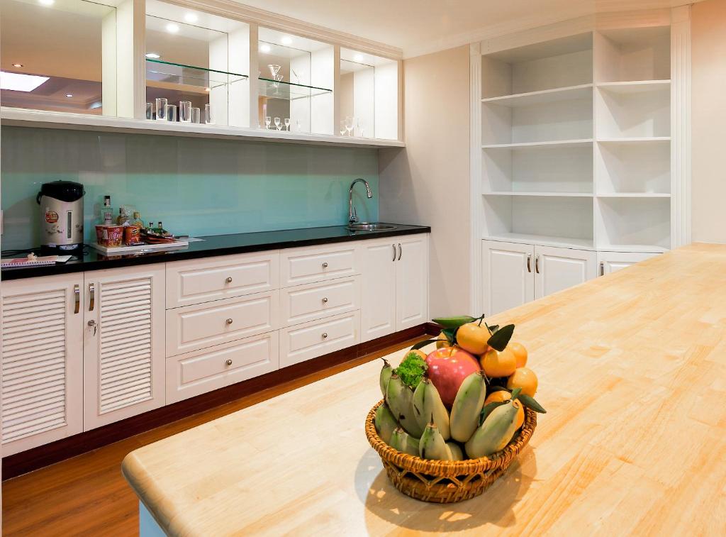 A built-in kitchenette with a sink, cabinets, open shelving and a fruit basket.