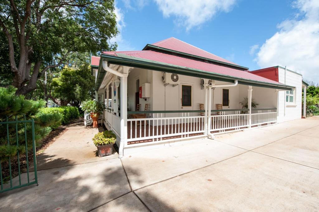 una pequeña casa blanca con techo rojo en Pure Land Guest House en Toowoomba