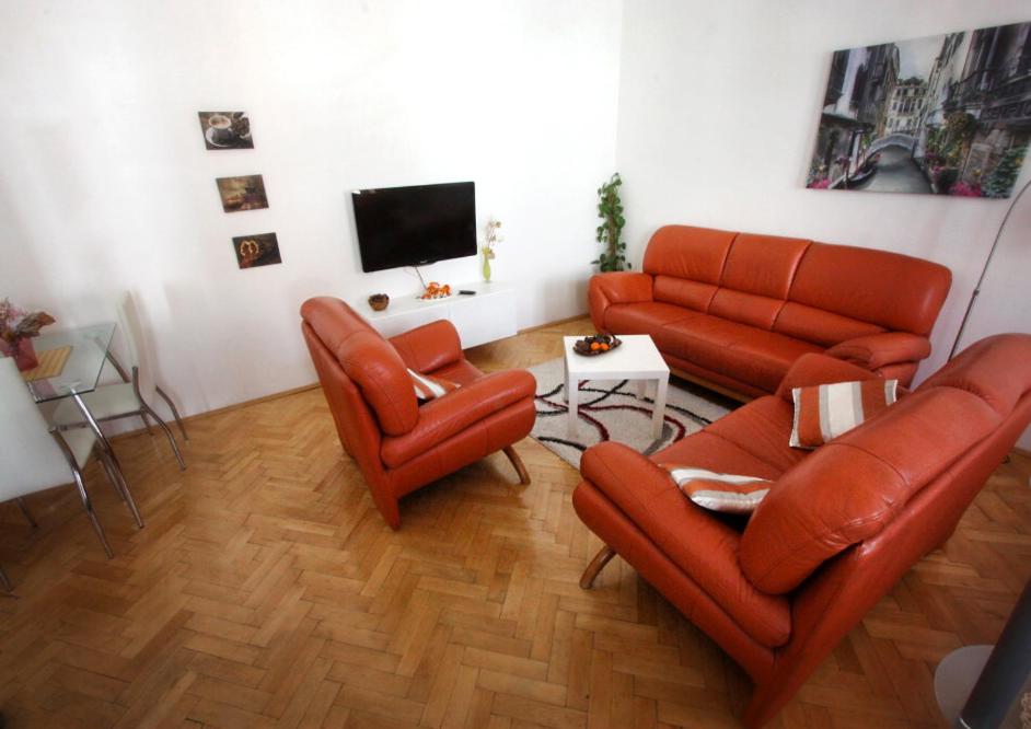 a living room with orange leather furniture and a flat screen tv at Apartmány u Arény Ostrava in Ostrava