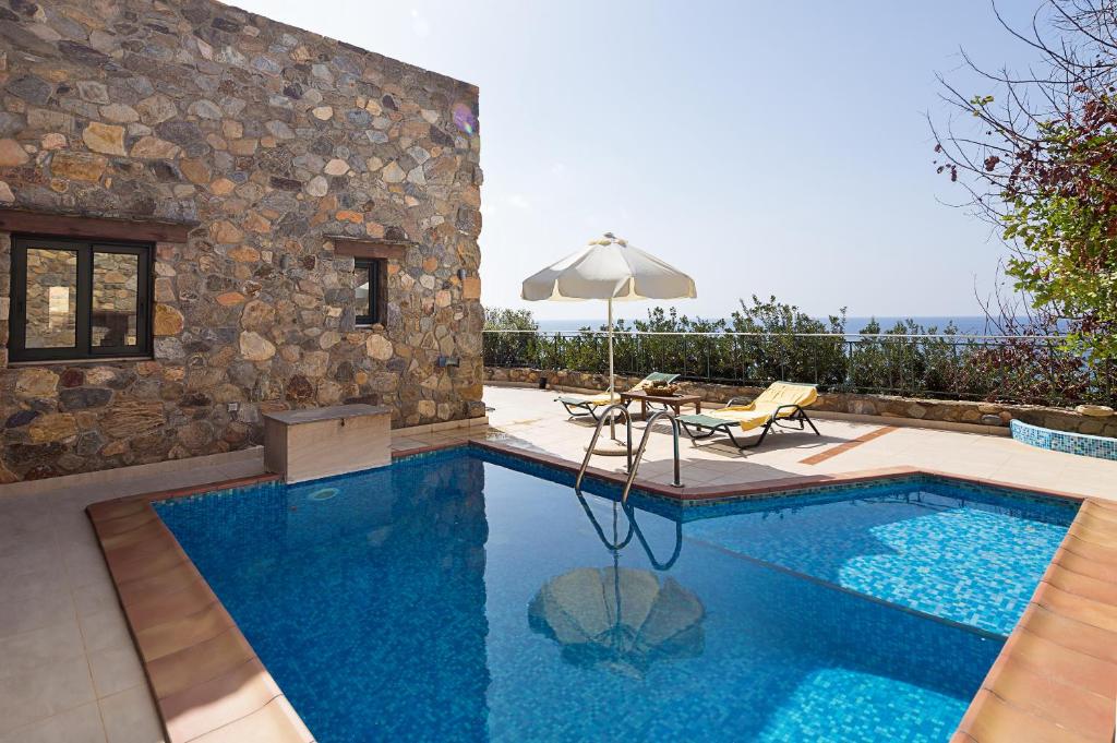 a swimming pool with a table and an umbrella at Meliti Sunset View & Private Pool Villa 20 min from Elafonissi in Livadia