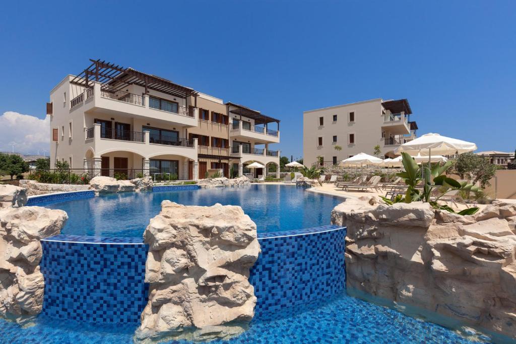 una piscina de agua azul frente a un edificio en Aphrodite Hills Rentals - Premium Serviced Apartments en Kouklia