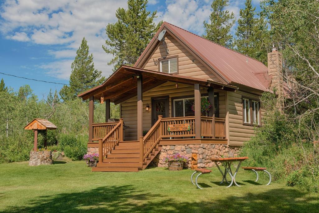 Cabaña de madera con porche y terraza en Grandma's Cabin Yellowstone Vacation Home, en Island Park