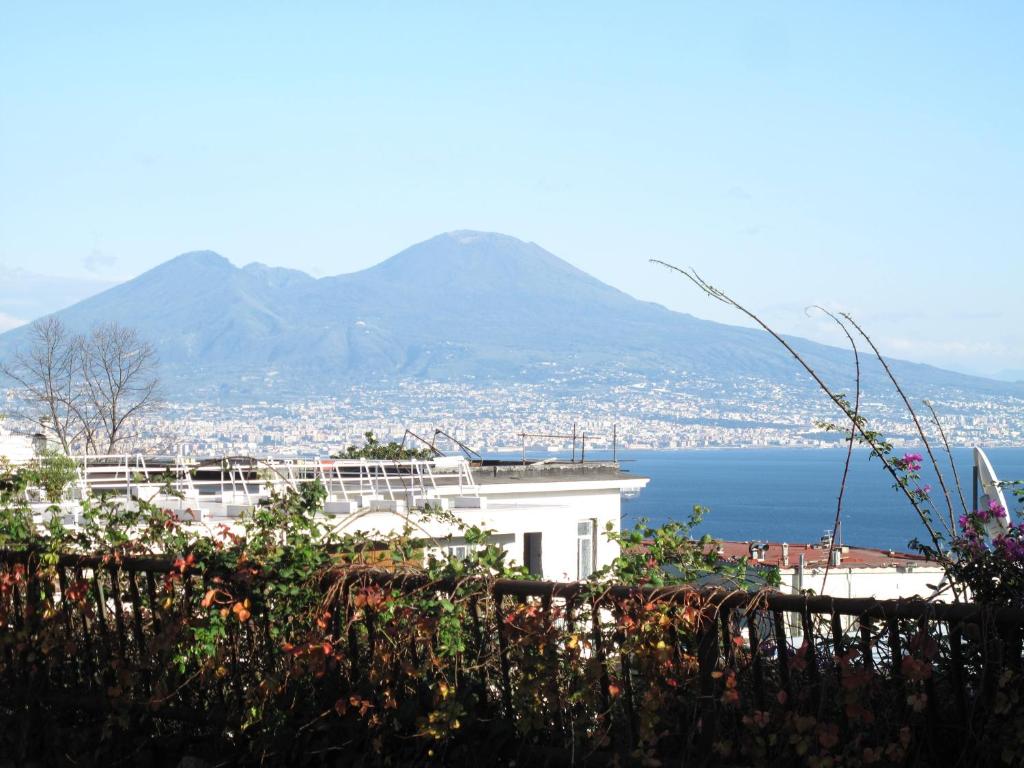 un edificio bianco con vista sull'acqua e sulle montagne di MONOCAMERA con TERRAZZOgiardino -STUDETTE -zona Panoramica POSILLIPO a Napoli