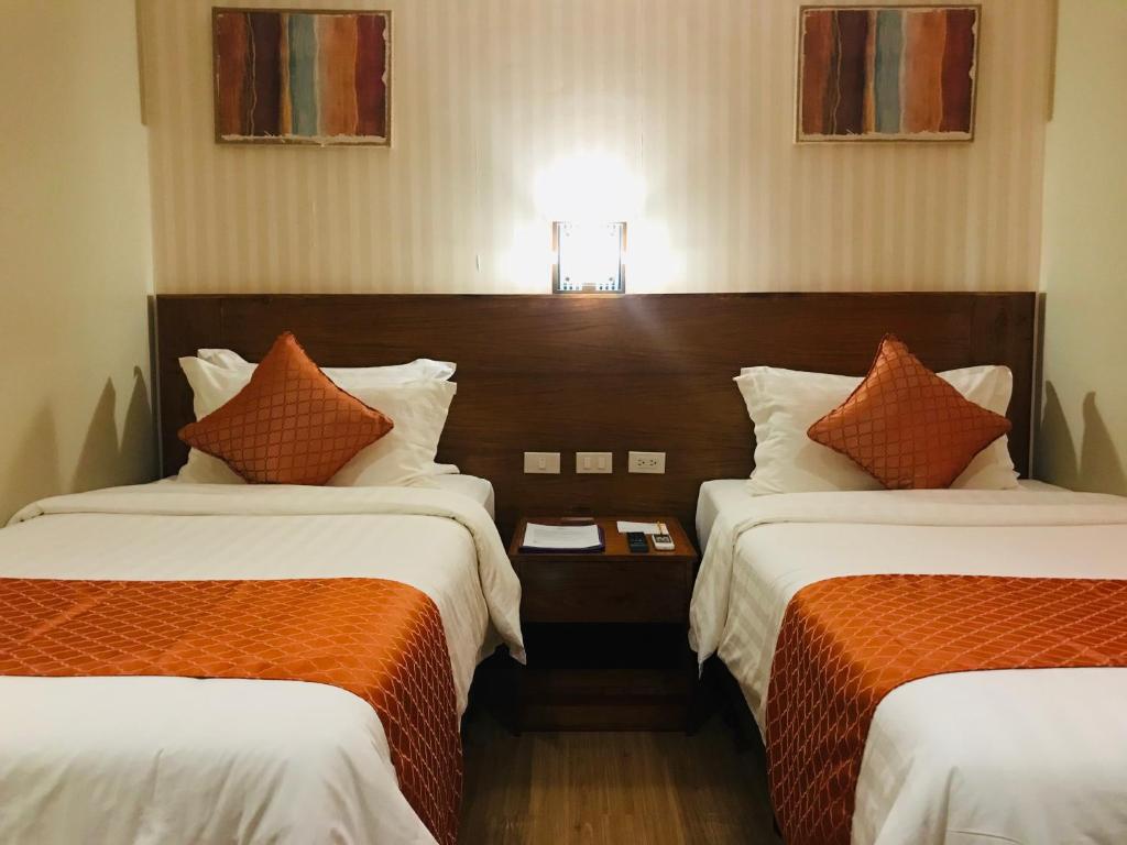 Cette chambre d'hôtel comprend 2 lits avec des draps orange et blancs. dans l'établissement Coron Soleil Express Hotel, à Coron