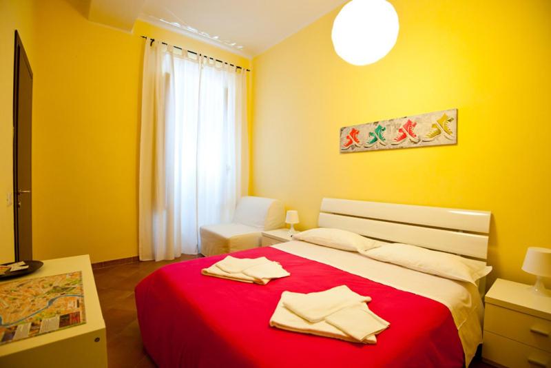 a yellow bedroom with a red bed with towels on it at Rome Services Porta Castello in Rome