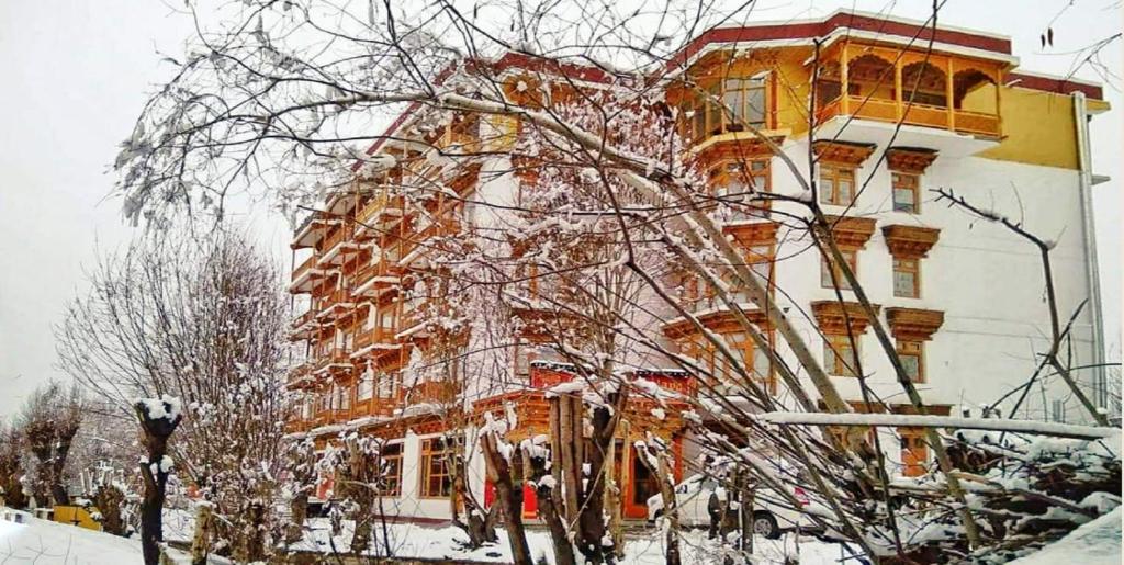 un grand bâtiment avec de la neige sur les branches d'un arbre dans l'établissement Hotel Grand Himalaya, à Leh