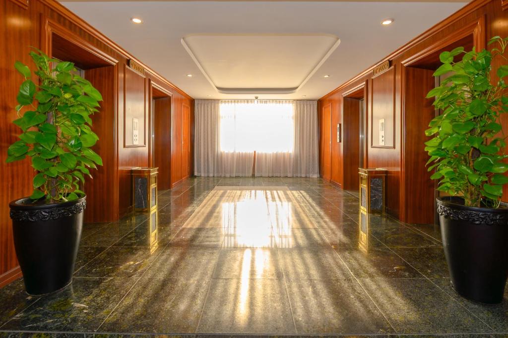 A glossy wood-paneled hotel corridor with lifts and a bright window at the end.