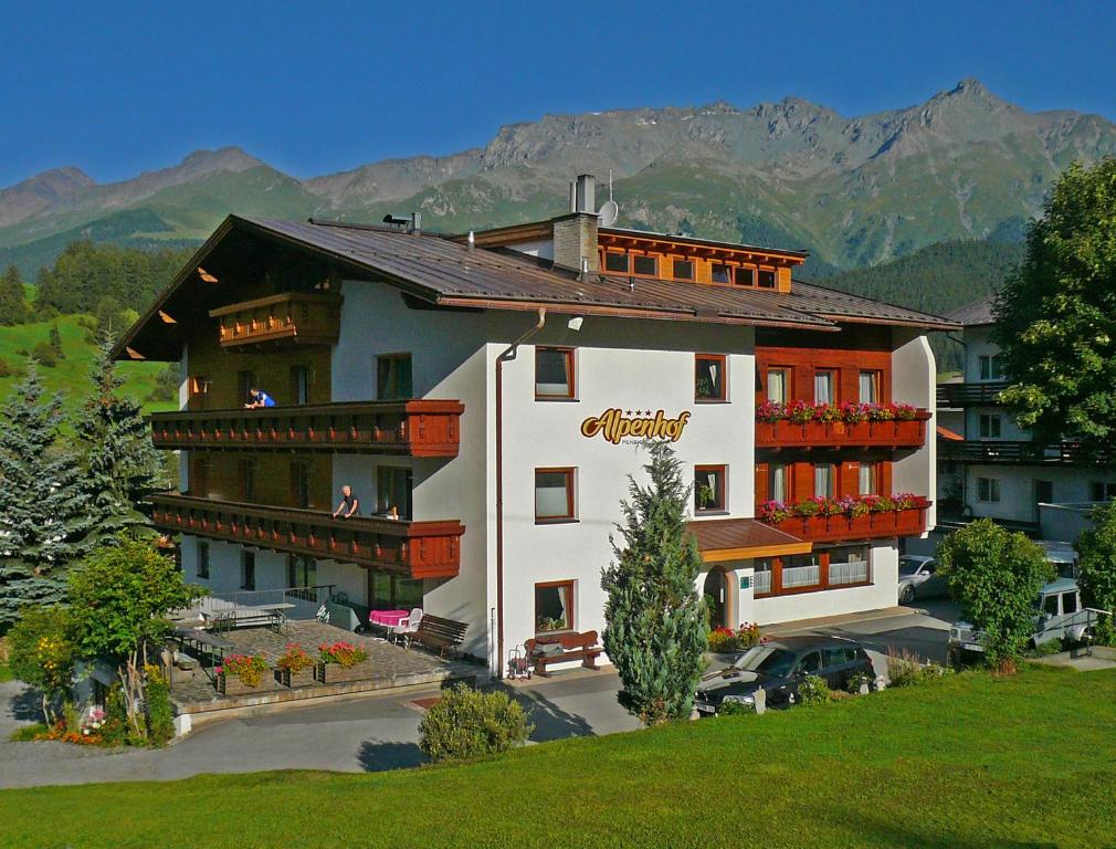 ein großes weißes Gebäude mit Balkonen und einem Berg in der Unterkunft Alpenhof Pension-Garni in Nauders