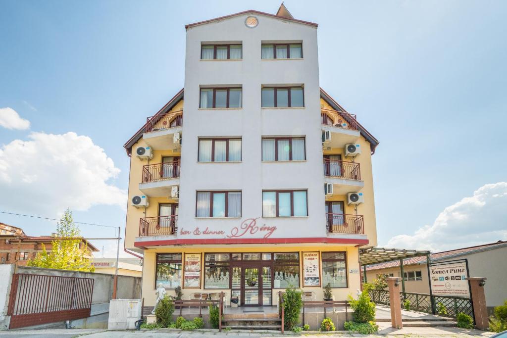 Ein hohes weißes Gebäude mit einem Schild drauf. in der Unterkunft Ring Hotel in Blagoewgrad