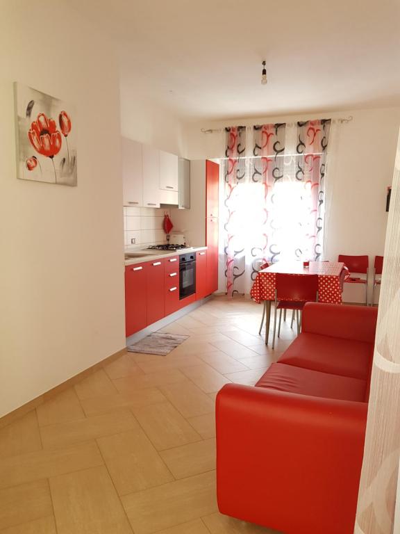 a living room with a red couch and a kitchen at Appartamento tra mare e montagna in Baunei