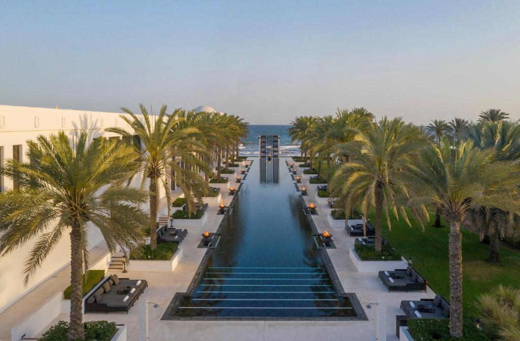 an aerial view of a swimming pool with palm trees at The Chedi Muscat in Muscat