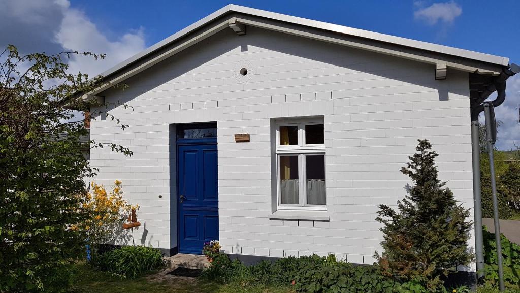ein weißes und blaues Haus mit blauer Tür in der Unterkunft Ferienwohnungen Unter den Linden in Thiessow