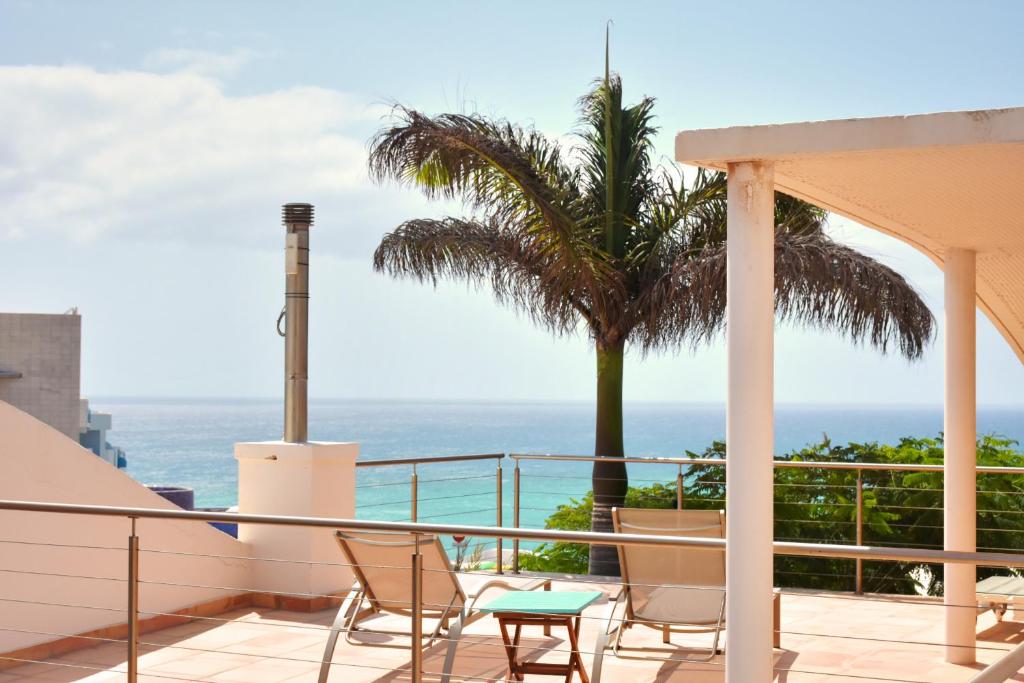 a balcony with chairs and a palm tree and the ocean at Villa MINEA II in Costa Calma