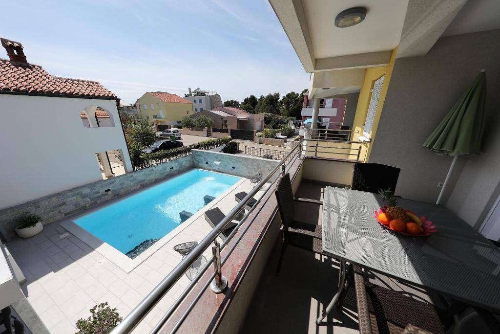 a balcony with a swimming pool and a table on a balcony at Luxury Villa Nada with Pool in Petrcane