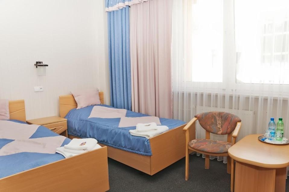 Pokój hotelowy z 2 łóżkami, stołem i krzesłem w obiekcie Vistula Hotel w mieście Świecie