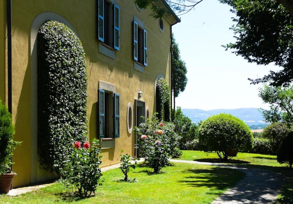 une maison jaune avec des fleurs dans la cour dans l'établissement poggio vaccaio appartamento A, à Binami