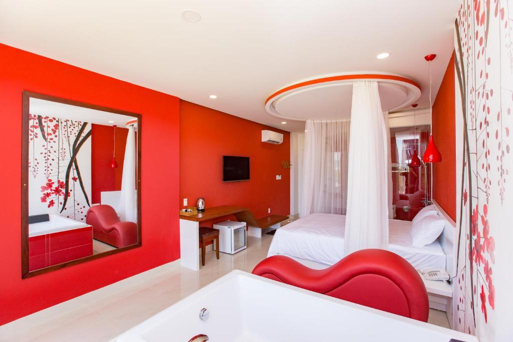1 dormitorio con paredes rojas, 1 cama blanca y bañera en Romely Hotel Nha Trang en Nha Trang