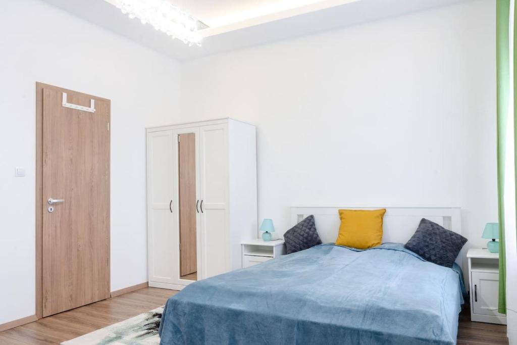 een witte slaapkamer met een bed met blauwe en gele kussens bij 3 En Suit bedroom flat in the main centre for 6ppl, 3BDR,3BTHR,AC in Boedapest