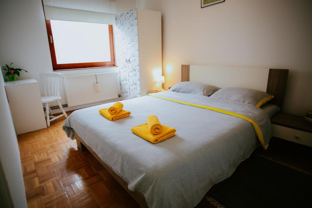 a bedroom with a large bed with yellow towels on it at Petros apartmani in Vukovar