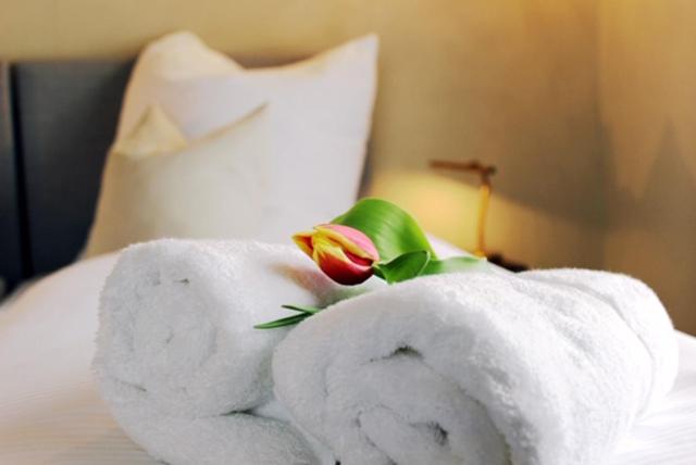 a towel with a flower on top of a bed at Altstadt Gästehaus in Lutherstadt Wittenberg