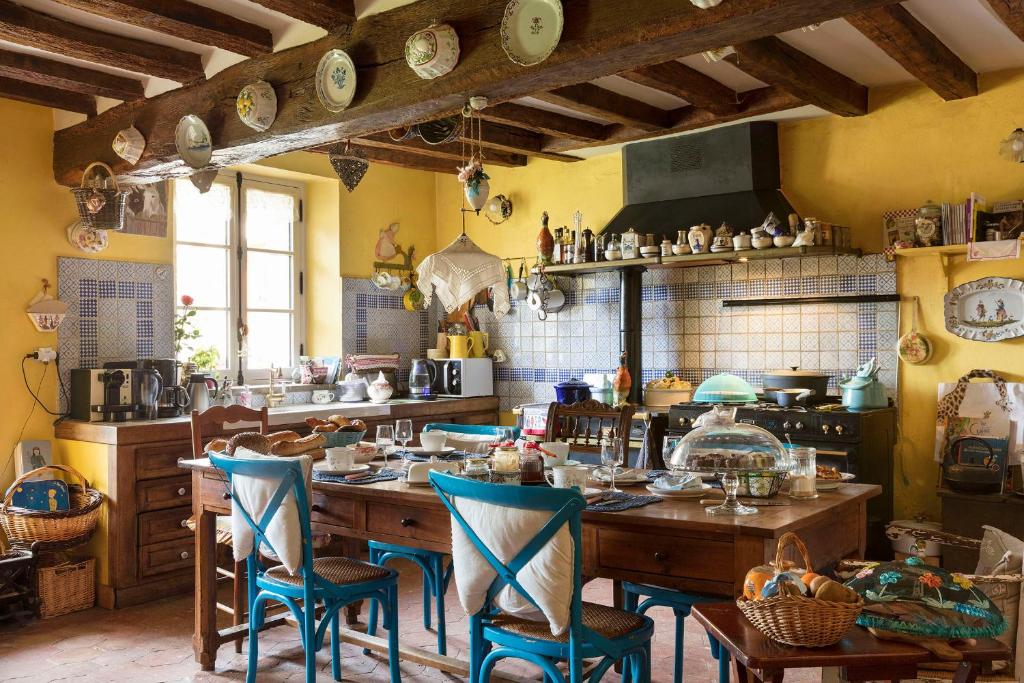 une cuisine avec une table en bois et des chaises bleues dans l'établissement Maison d'Hotes à l'Ombre Bleue, à Mittainville