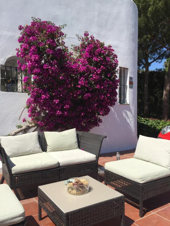 a garden with two chairs and a bush with pink flowers at Fascinating & Luxurious Golf,Mountain & Garden view apartment Porto Banus in Marbella