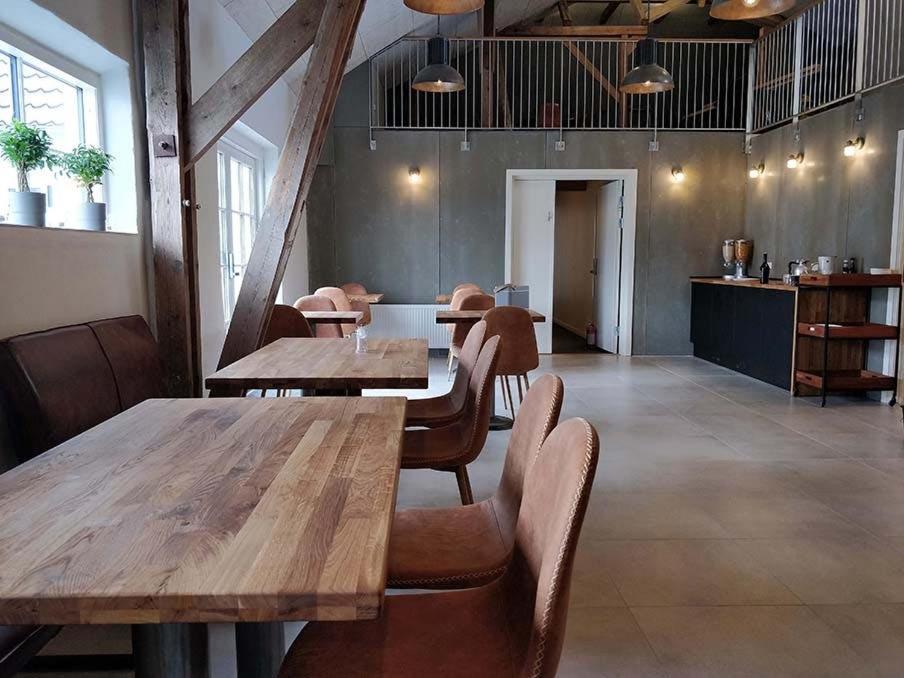 un restaurante con mesas de madera y sillas en una habitación en B & B Gødstrup - cafe og restaurant Den Gamle Stald en Herning