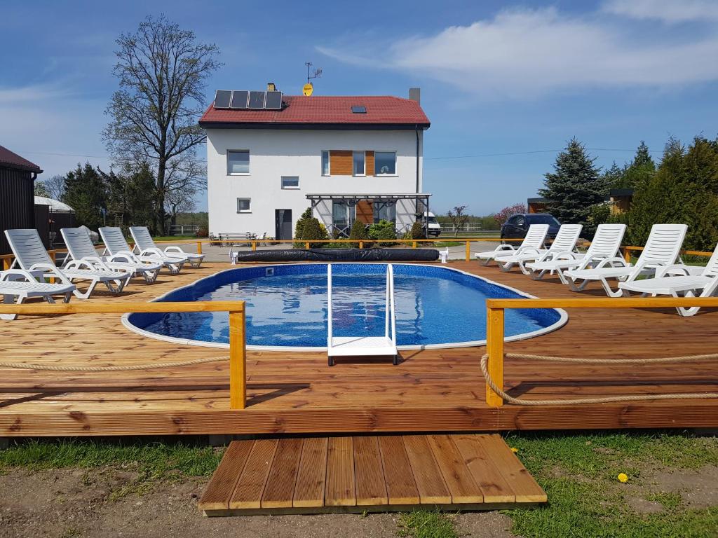 a swimming pool with chairs and a house at Noclegi Beata in Dąbki