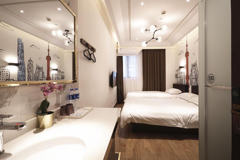 uma casa de banho com 2 camas, um lavatório e um espelho. em Meego Yes Hotel em Xangai