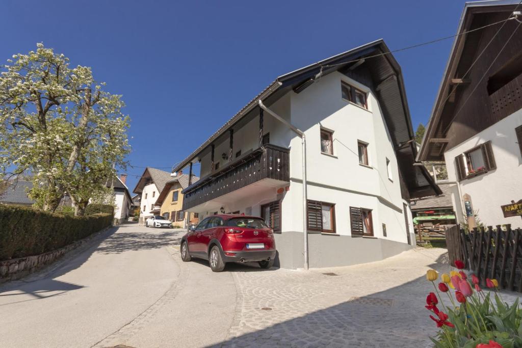 un coche rojo estacionado junto a un edificio blanco en Lake Bled Holiday Home, en Bled