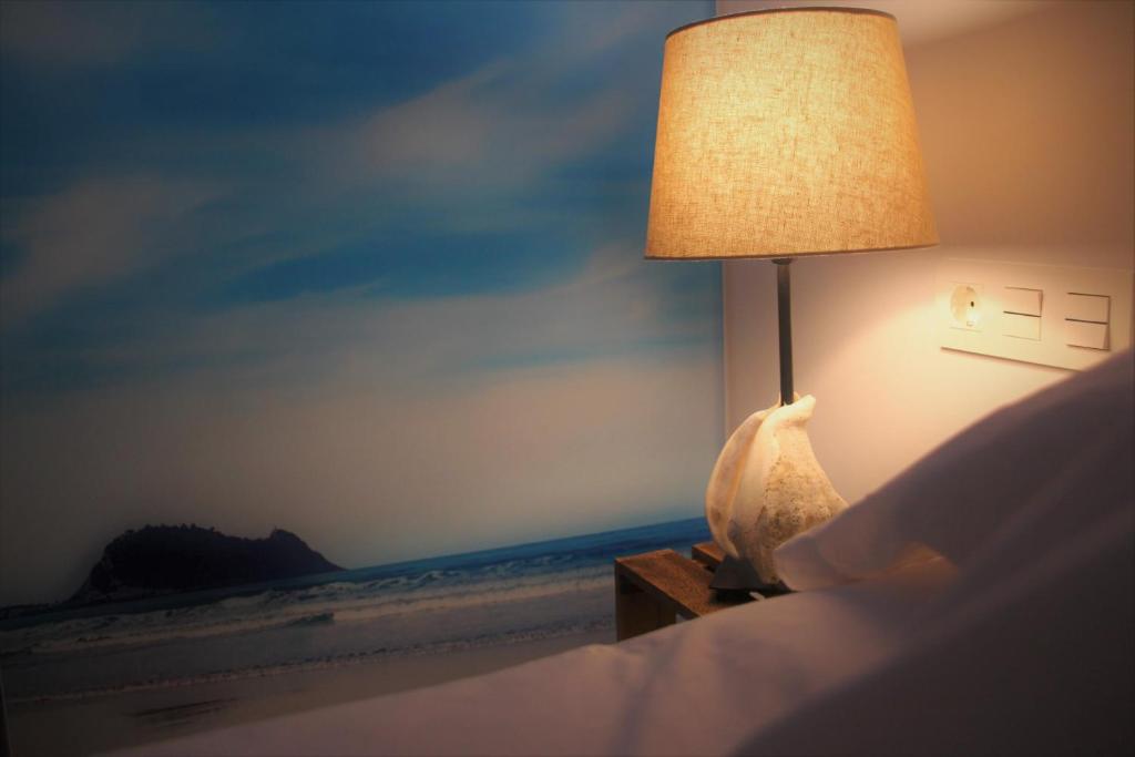 una lámpara sentada en una cama junto a una playa en Apartamentos Zarautz Centro, con tarjeta parking gratis en zona azul y residentes en Zarautz