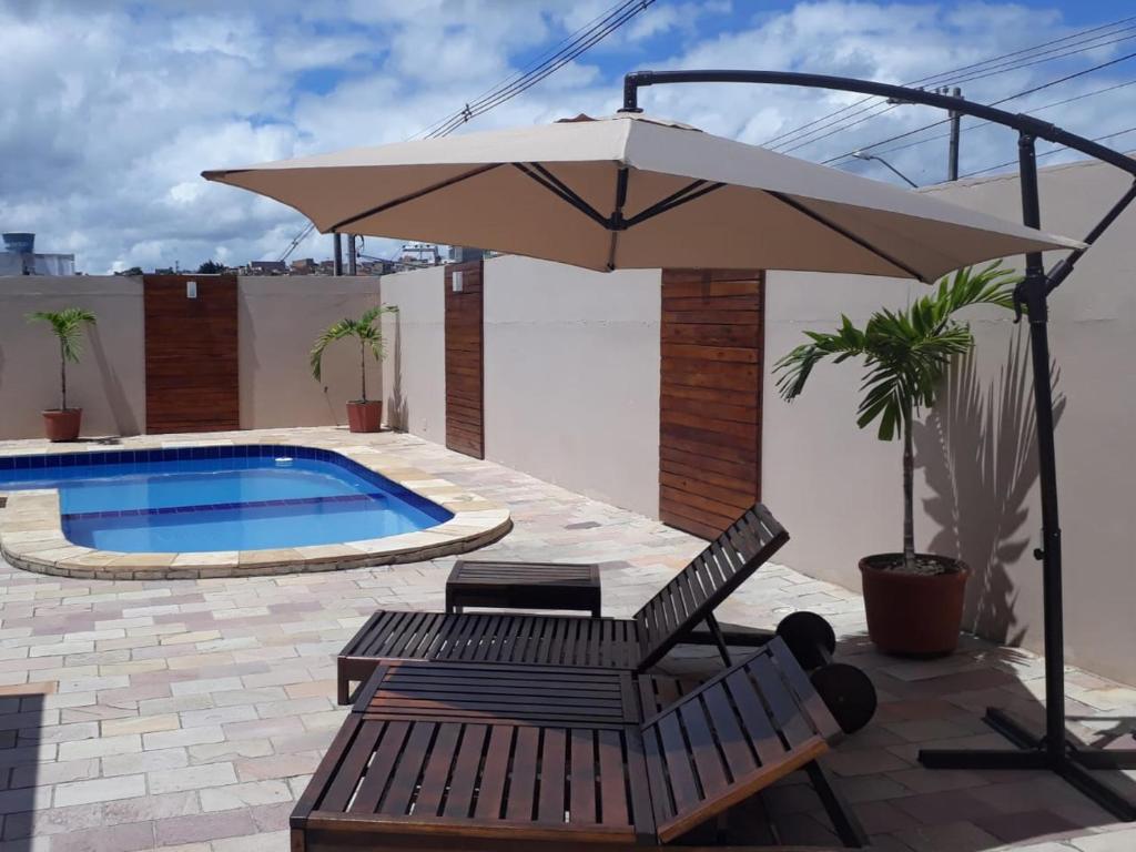 a patio with an umbrella and chairs and a pool at Hotel Itaparica in Caruaru