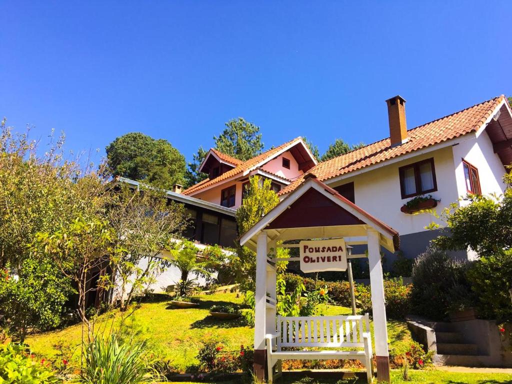 a house with a for rent sign in front of it at Pousada Oliveri in Monte Verde