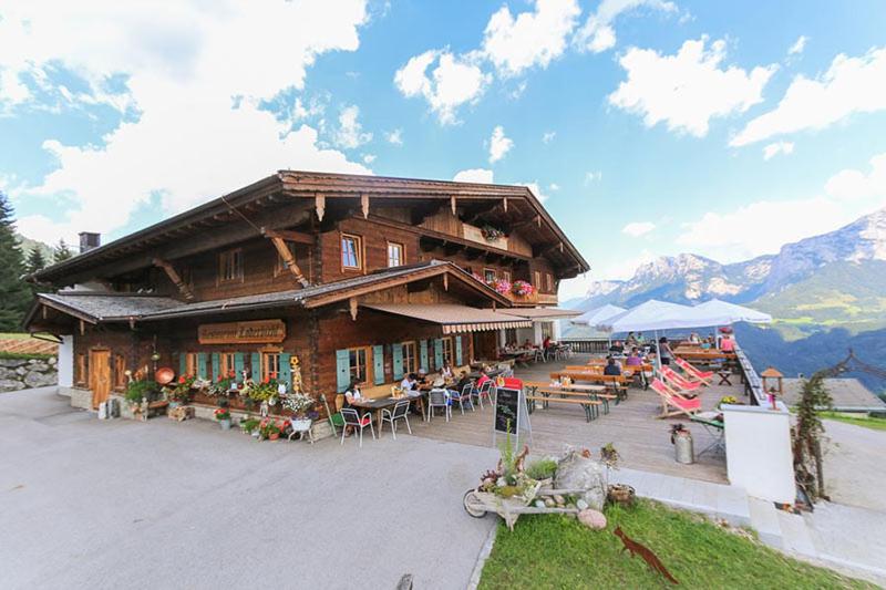 un edificio con mesas y sillas delante de él en Ferienhaus Loderbichl, en Lofer