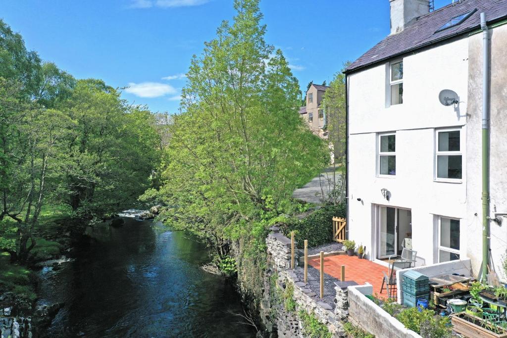 a river in front of a white building and a street at Glanafon Cottage in Bethesda