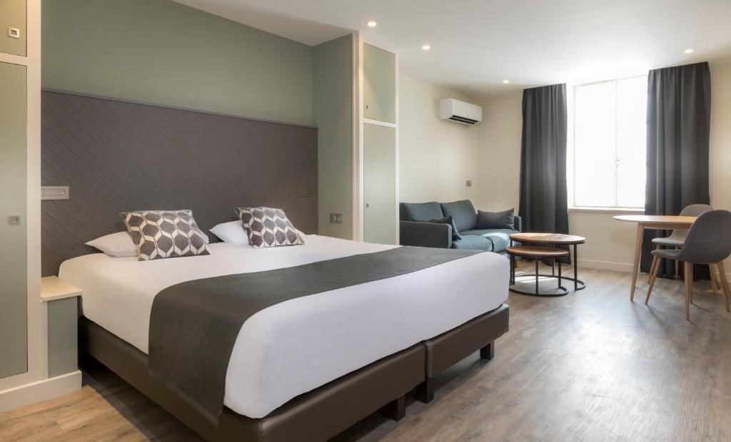ein Hotelzimmer mit einem großen Bett und Stühlen in der Unterkunft Residence The Originals Demeure des Remparts in Provins