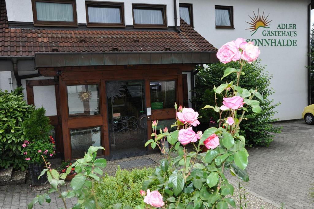 a restaurant with pink roses in front of a building at Gasthof Adler Güttingen in Güttingen