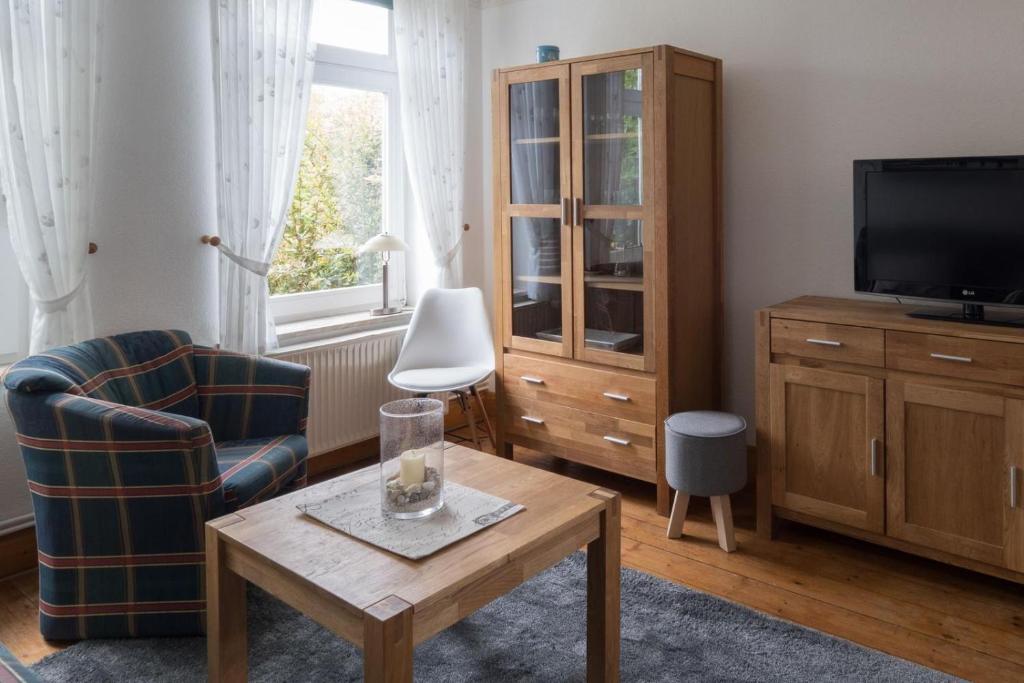 een woonkamer met een tv en een stoel en een tafel bij Terrassenwohnung-Loenneberger-im-Ferienhof-Nielson in Bisdorf