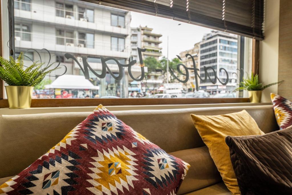 a couch with pillows sitting in front of a window at Abc Hotel in Thessaloniki