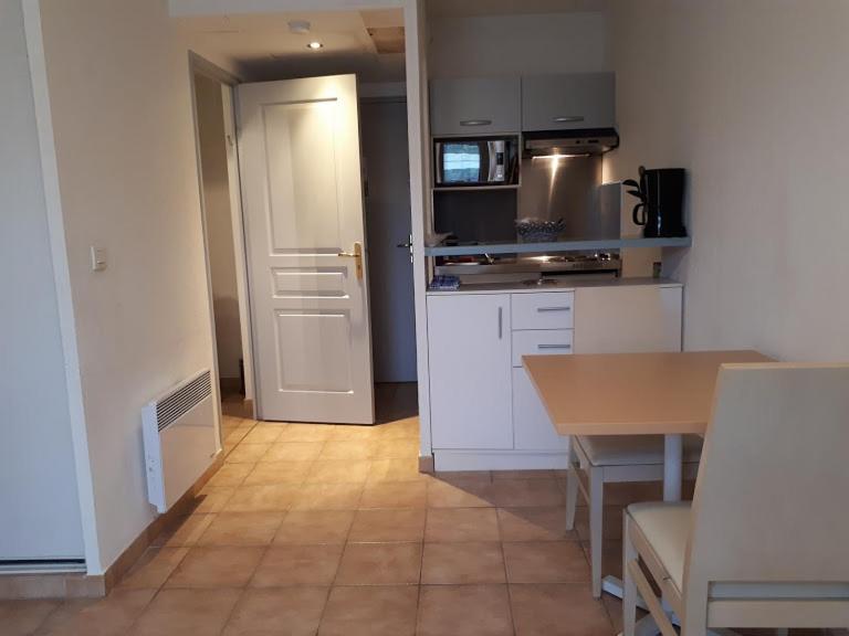 a kitchen with white cabinets and a table and a door at Domaine de l'Albatros in Mouans-Sartoux