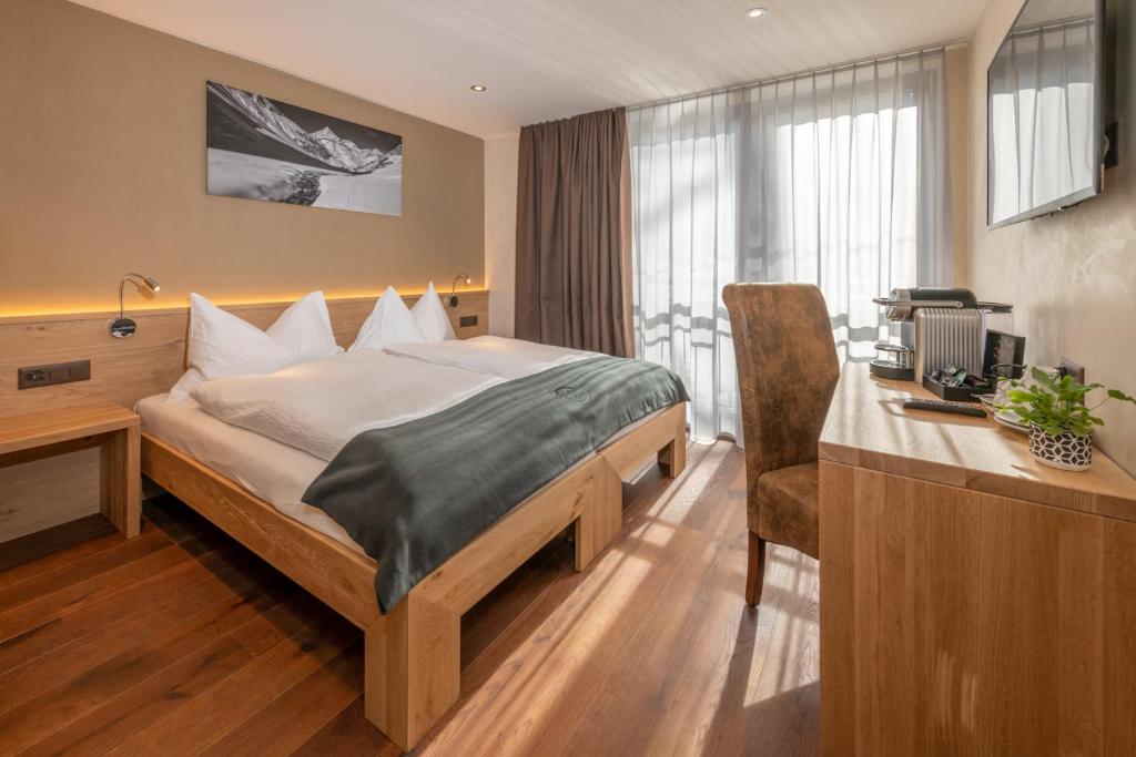 una camera d'albergo con letto e scrivania con computer di Hotel Heimatlodge a Sankt Niklaus