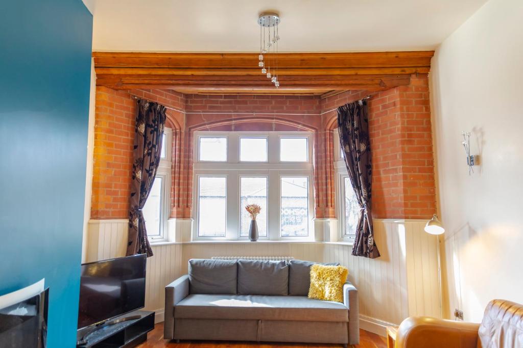 een woonkamer met een bank en een raam bij Apartment No 1 - The Old Red King Pub, Whitefield, Manchester in Manchester